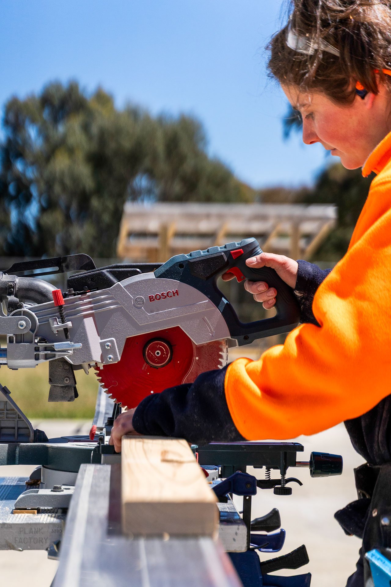A construction worker in a hi-vis vest operating a circular saw on site