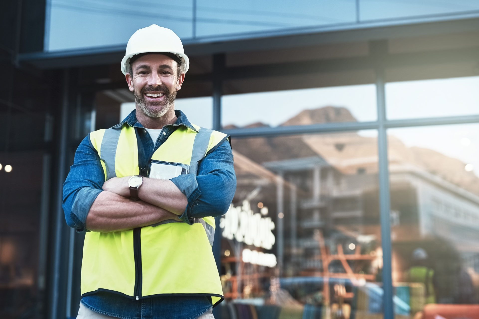 A construction professional in a hard hat and hi-vis vest on a building site