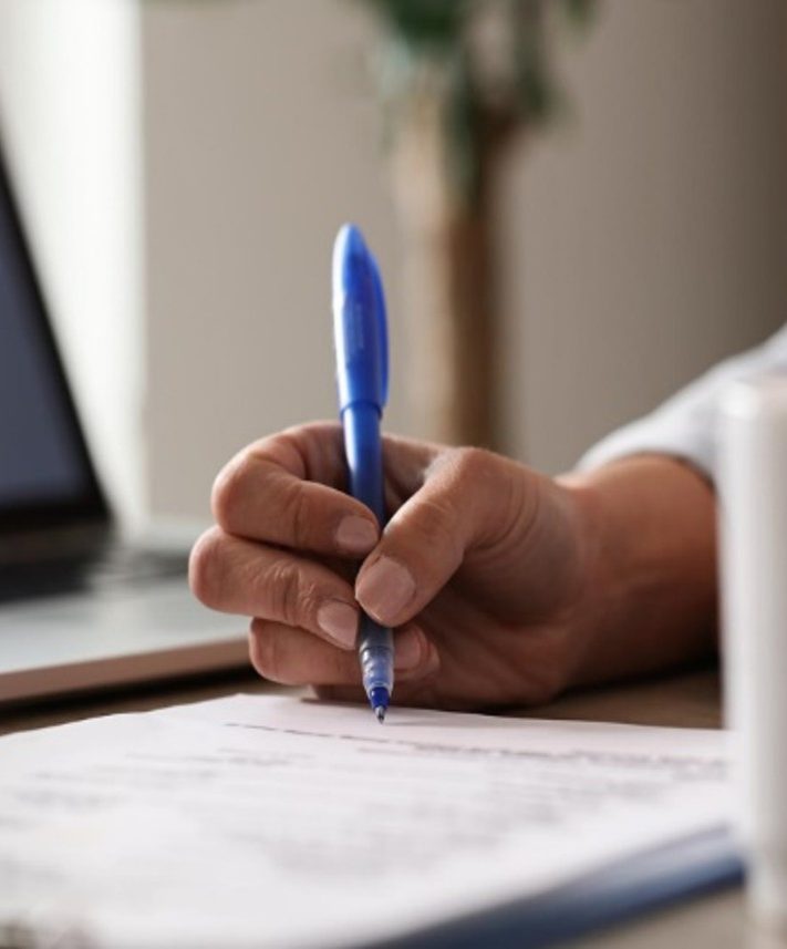 A hand holding a pen over a contract document on a desk.