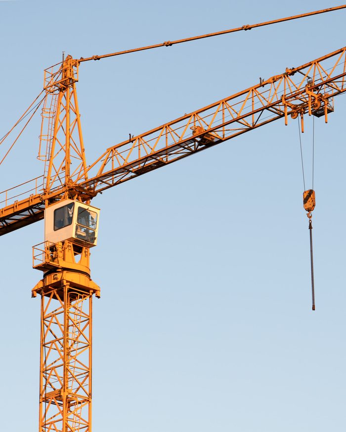 Tower cranes over a construction site with the city behind.