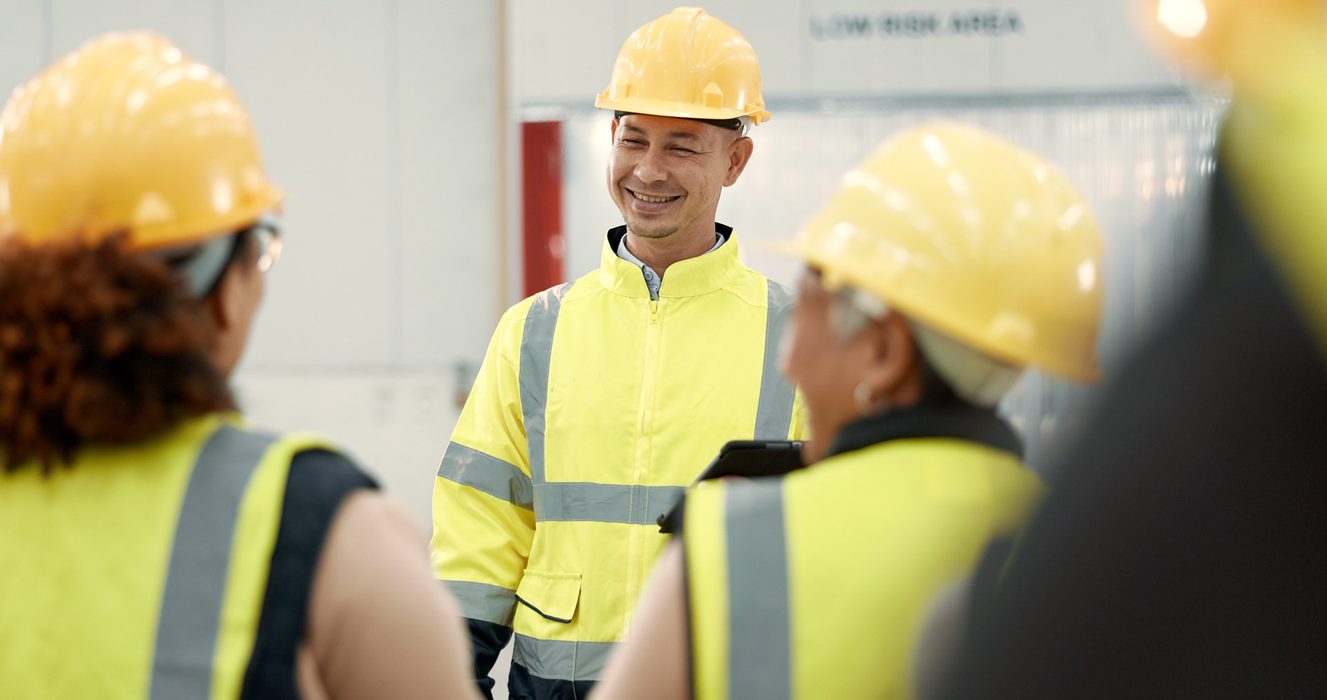 Builders in hard hats discussing plans on a construction site.