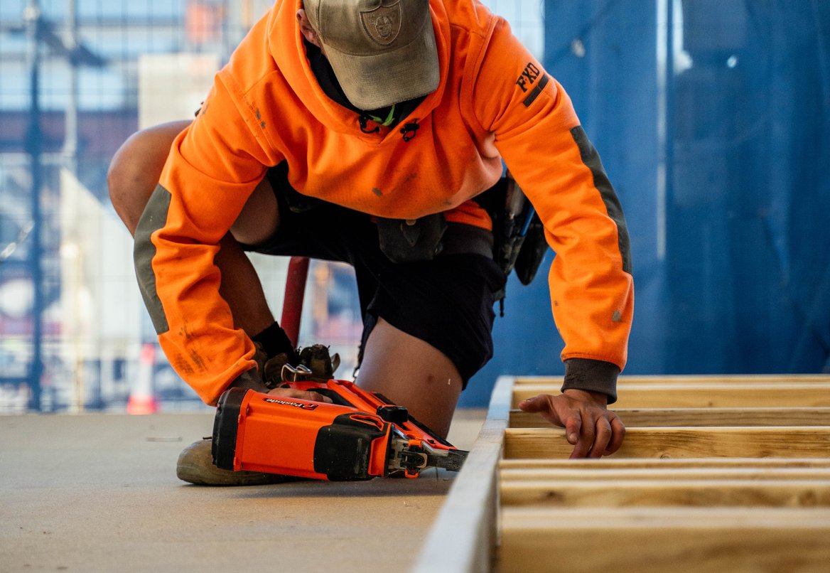 Apprentice measuring timber at a workbench