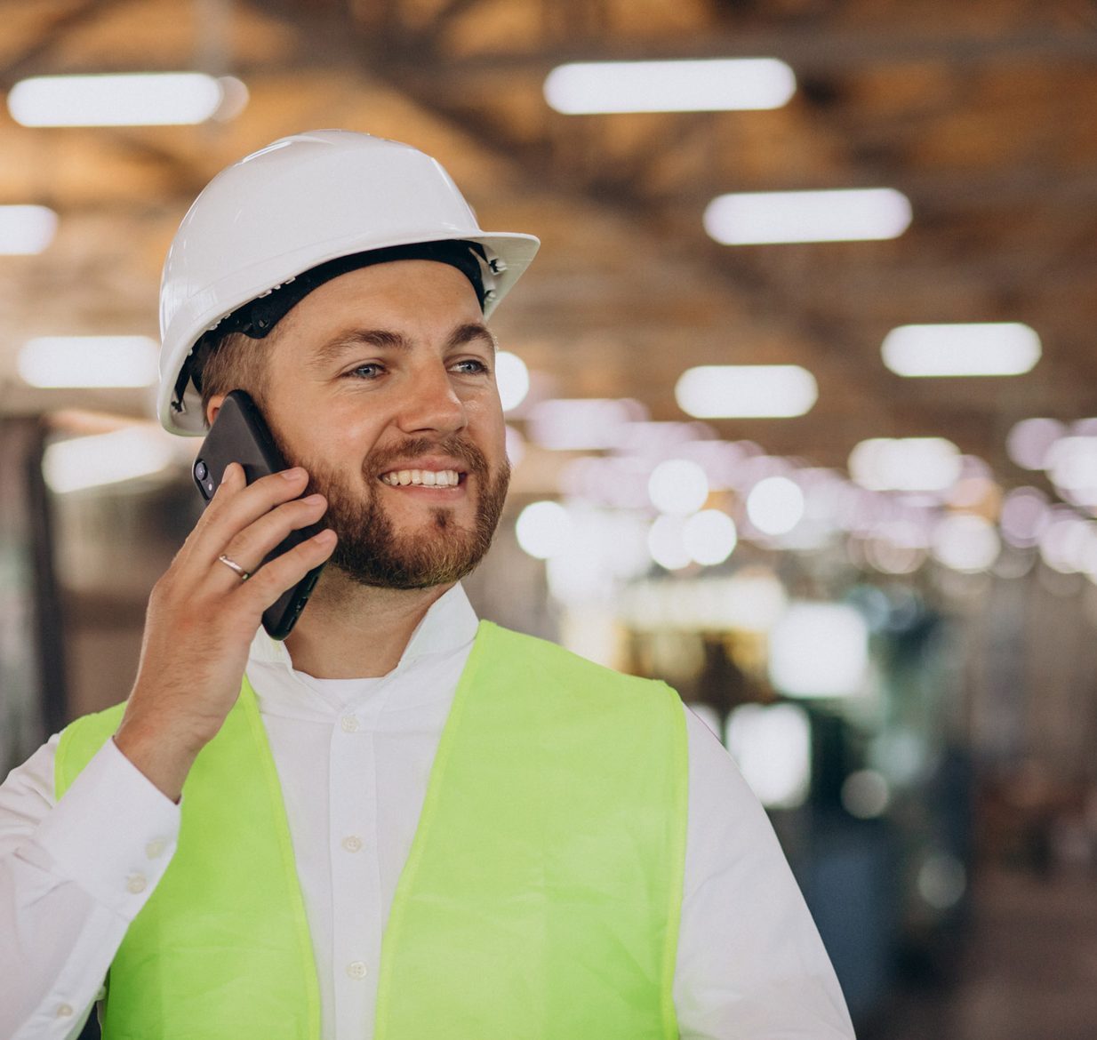 A young engineer on the phone on a factory floor.