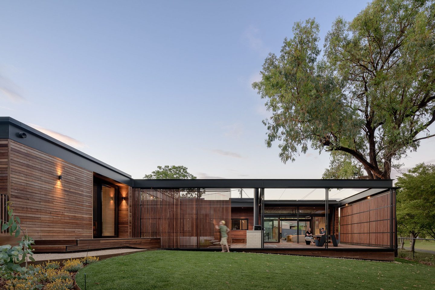 A contemporary Canberra home with timber cladding and large windows at dusk