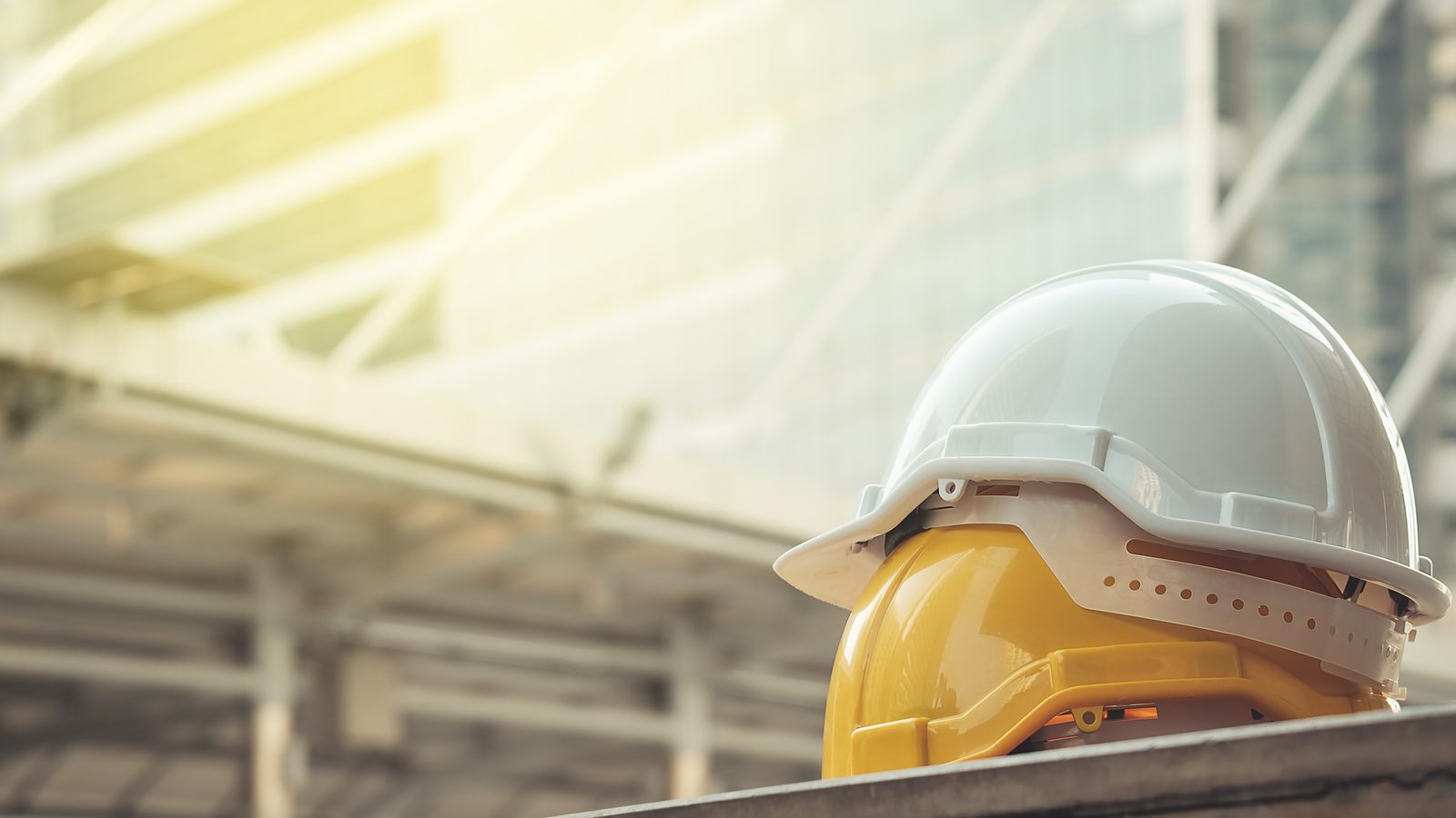 Blue and yellow safety hard hats positioned on construction site with building framework in background