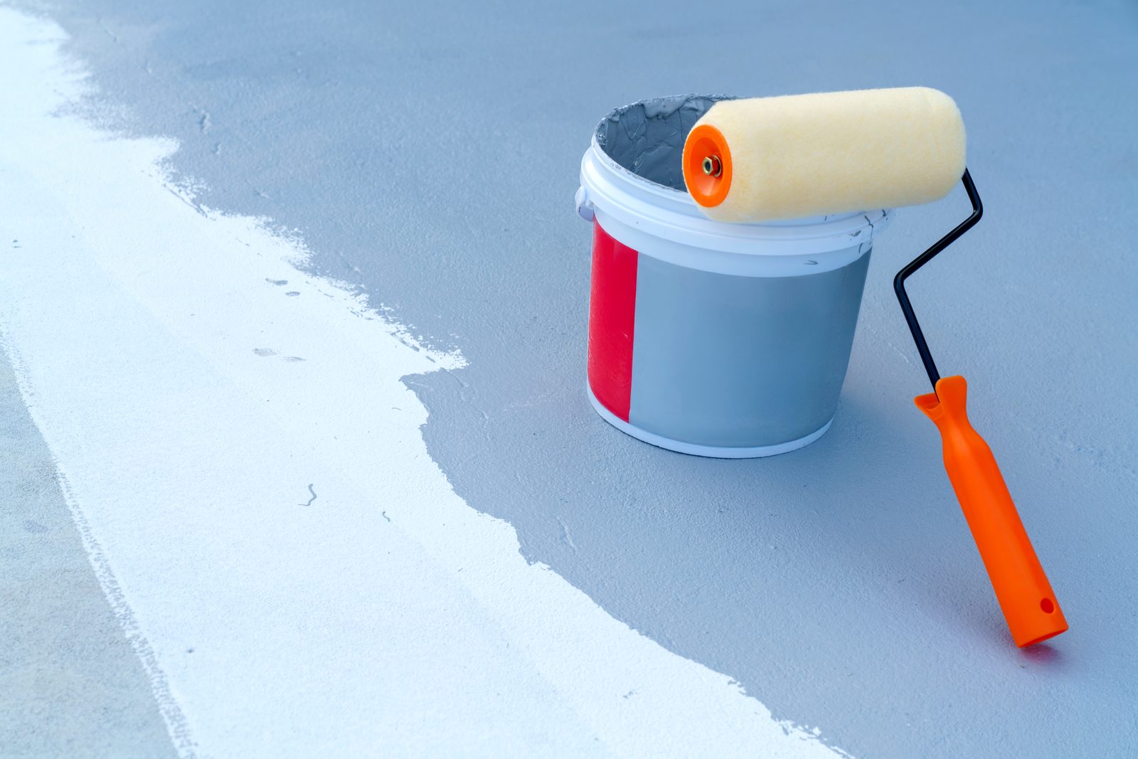 Paint roller applying waterproofing coating to concrete surface