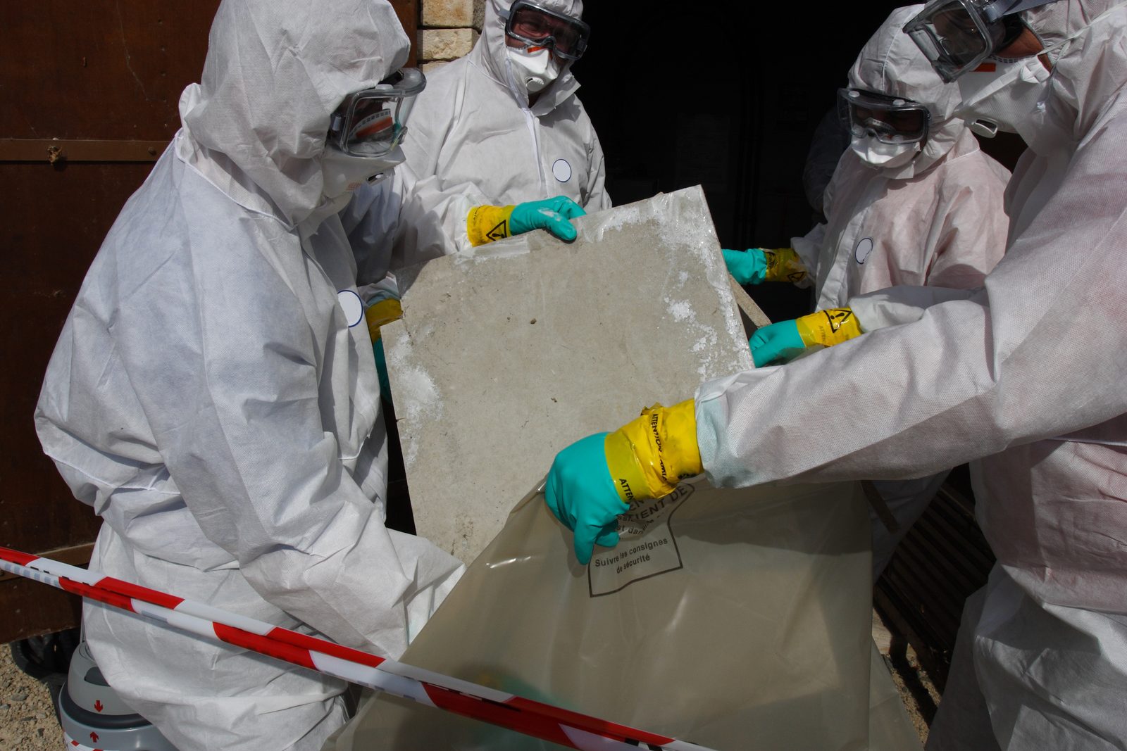 Workers in protective suits handling asbestos-containing material