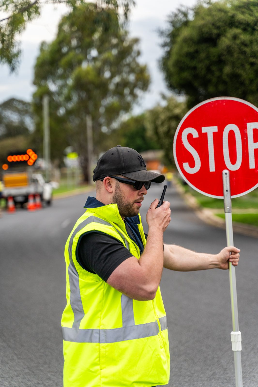 Construction site traffic management worker holding a red STOP sign wearing high-visibility clothing